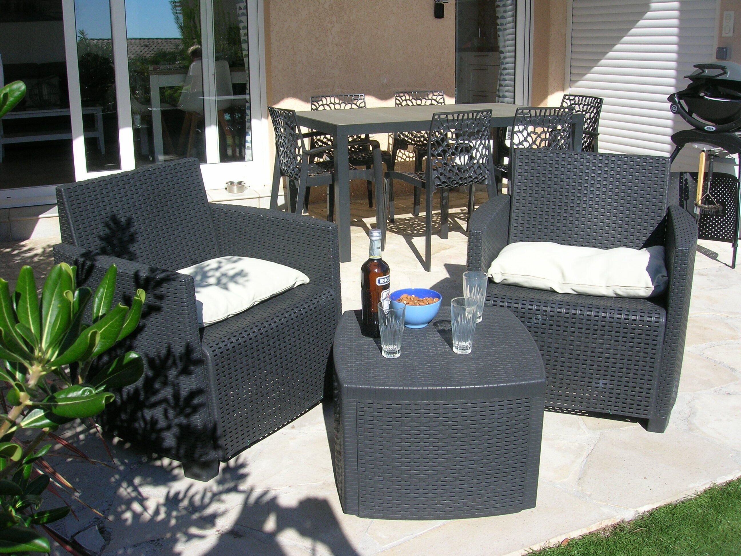 Een terras buiten met rieten meubels, een tafel en een schaal met lekkernijen.