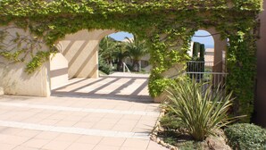 An outdoor corridor with a tiled floor, a stone wall, and a metal gate. - 3P RDJ air-conditioned apartment in residence with swimming pool and tennis court in St Aygulf (Unknown)