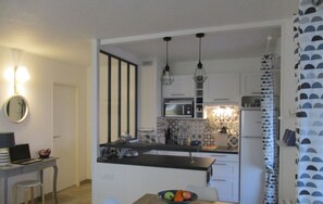 Uma cozinha moderna com uma ilha central, uma área de refeições com mesa e cadeiras, e um pequeno espaço para cozinha.
