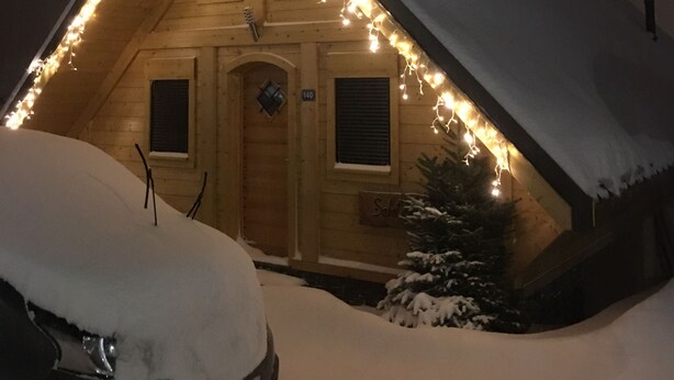 A snow-covered building with a sloped roof, illuminated by string lights, and a sign indicating the number 140. - CHALET SABOT OF STANDING VENUS AT THE FOOT OF TRACKS (Fontcouverte-la-Toussuire)