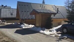 A building with a sloped metal roof, a wooden door, and a small porch area. - CHALET SABOT OF STANDING VENUS AT THE FOOT OF TRACKS (Fontcouverte-la-Toussuire)