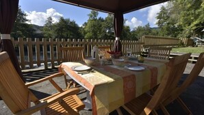 Un espacio de comedor al aire libre con una mesa lista para cuatro personas, rodeada de sillas de madera.