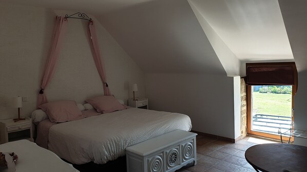 A bedroom with a bed, bedside tables, a bench, a window with a view, and a door.
