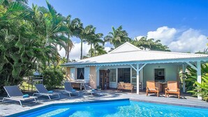 A poolside area with lounge chairs and a small building with a white roof.