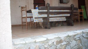 A stone wall, a wooden bench, and a table with chairs in a covered outdoor area. - CARQUEIRANNE APARTMENT WITH POOL 2MN BEACH (Carqueiranne)