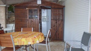 A wooden structure with a clock, a table with chairs, and a refrigerator. - CARQUEIRANNE APARTMENT WITH POOL 2MN BEACH (Carqueiranne)
