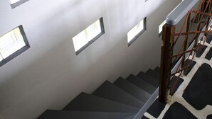 A staircase with a black and white patterned floor, a wooden handrail, and a metal railing.