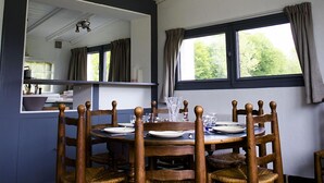 A dining area with a round table, wooden chairs, and a hanging pendant light.