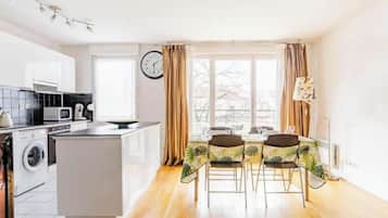 Una cocina moderna con una isla central, una zona de comedor con mesa y sillas, y un ventanal con cortinas.