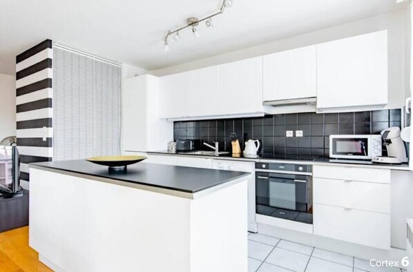 A modern kitchen with white cabinets, a black countertop, and a central island. - Magnificent, bright, modern and very quiet apartment with terrace. (Lyon)