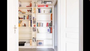 Ein weißes Bücherregal mit verschiedenen Gegenständen, darunter Bücher, Dekorationsobjekten und einer kleinen schwarzen Box.