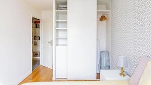 Ein Schlafzimmer mit Kleiderschrank, Nachttisch und einer Wand mit Muster.