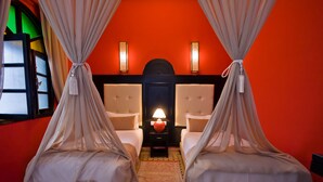 A room with two beds, a red wall, and a small table with a lamp. - Family room for 4 people. (Essaouira)
