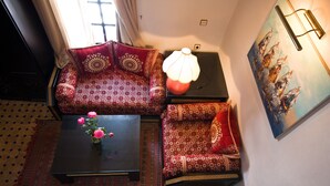 A room with a sofa set, a coffee table with flowers, a lamp, and a painting on the wall. - Family room for 4 people. (Essaouira)