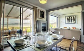 Comedor con mesa dispuesta para cuatro personas, ventanas amplias y vistas al exterior.