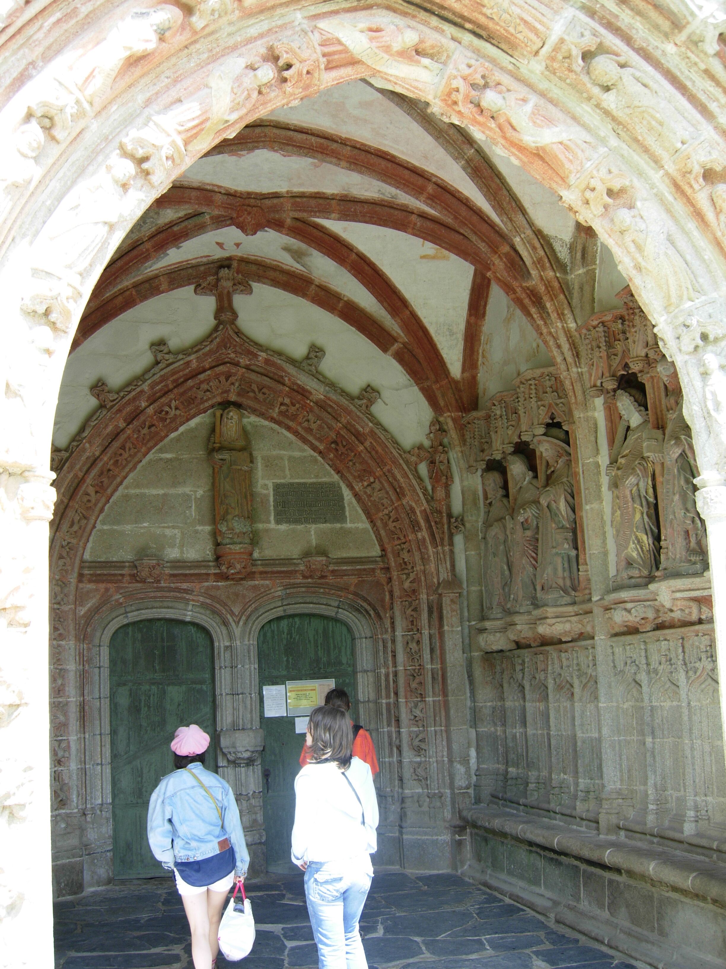 An arched doorway with intricate stone carvings and a green door.