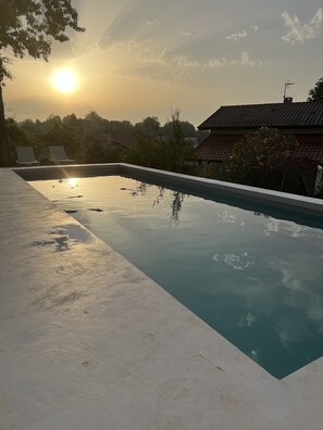 A rectangular swimming pool with a clear edge, surrounded by a concrete deck. There are two lounge chairs on the left side of the pool. - Villa 8 people Basque side Bidart (Bidart)