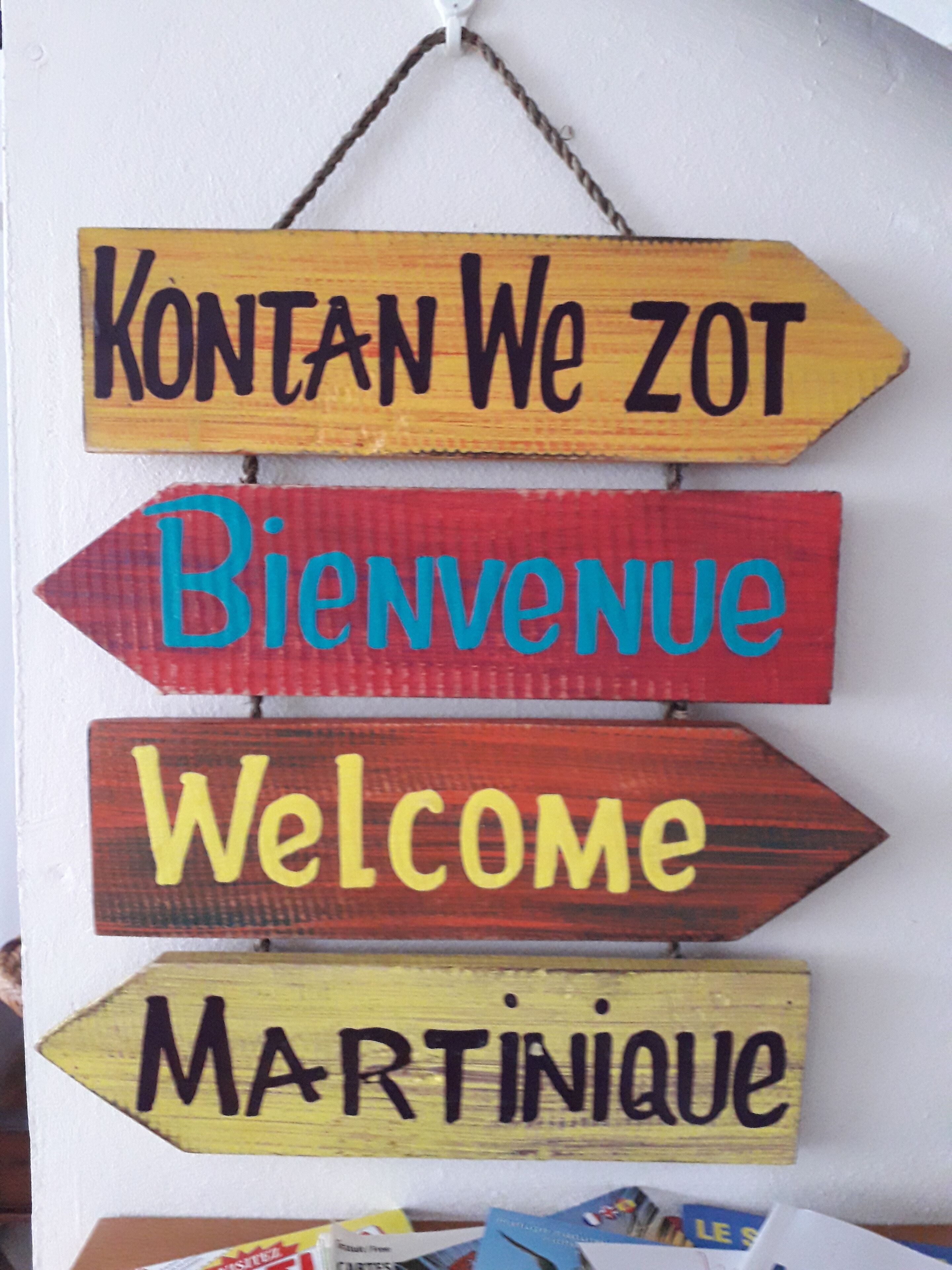 Een houten bord met verschillende pijlen, elk voorzien van een andere begroeting in diverse talen.