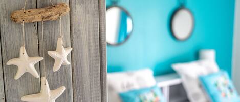 A room with a wooden door, a bed with white bedding, and a blue wall with two round mirrors.