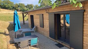 Un bâtiment en bois doté d’un patio comprenant une table et des chaises, ainsi que d’un espace salon abrité.