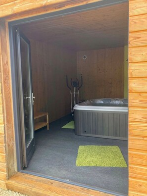 Een houten interieur met een jacuzzi, een deur en een klein bankje.