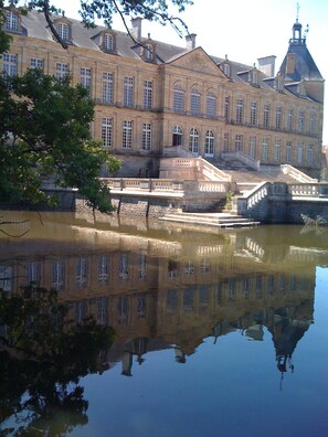 Un bâtiment historique avec un grand plan d’eau aux reflets saisissants à sa devanture.