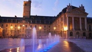 Un cortile con fontana e architettura classica, tra cui un grande edificio con colonne e una torre.