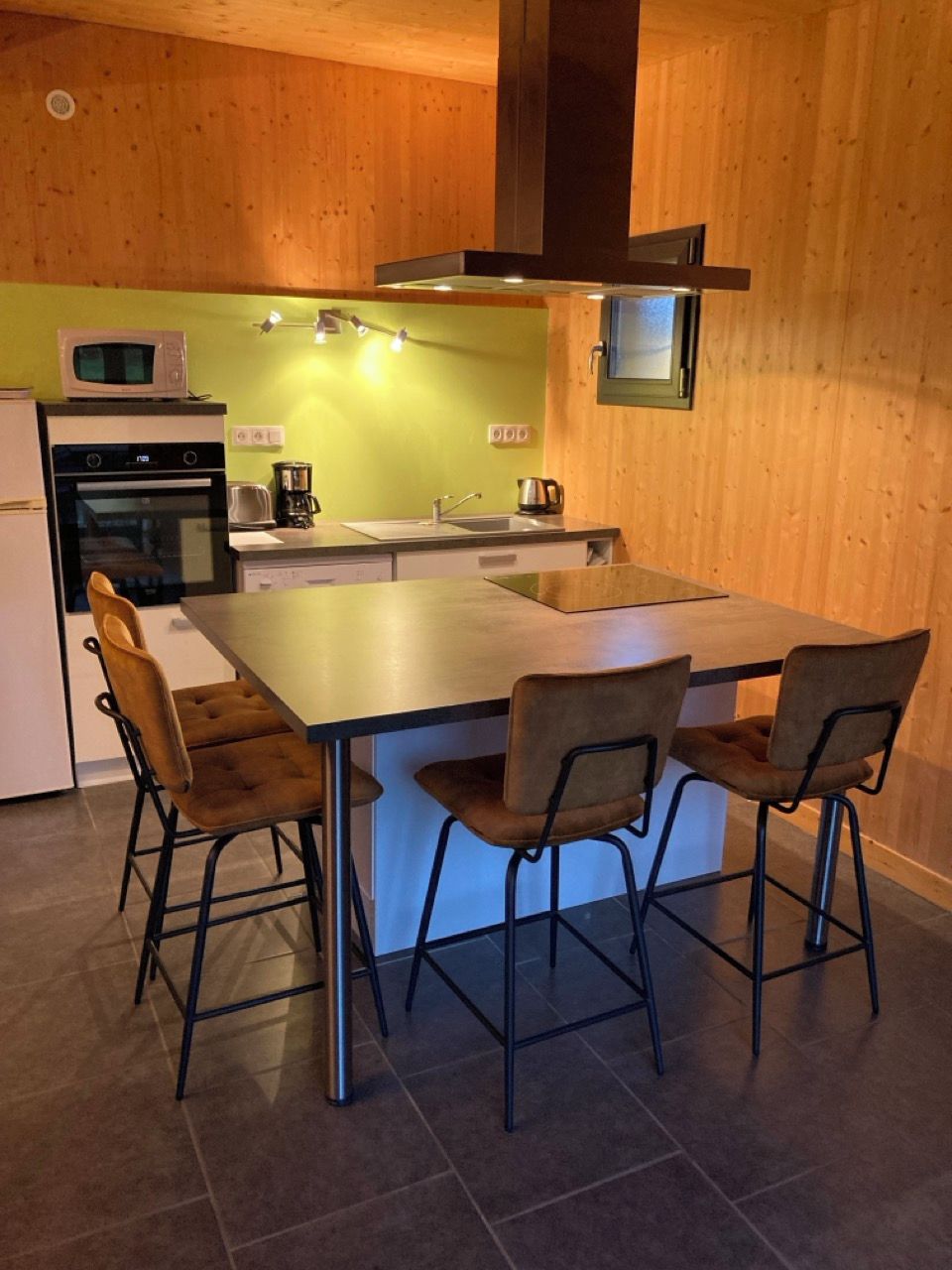 Une cuisine compacte dotée d’un îlot central, d’un four à micro-ondes, d’une cuisinière et d’un évier.