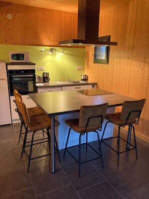 Een compacte keuken met een centraal eiland, een magnetron, een kookplaat en een spoelbak.