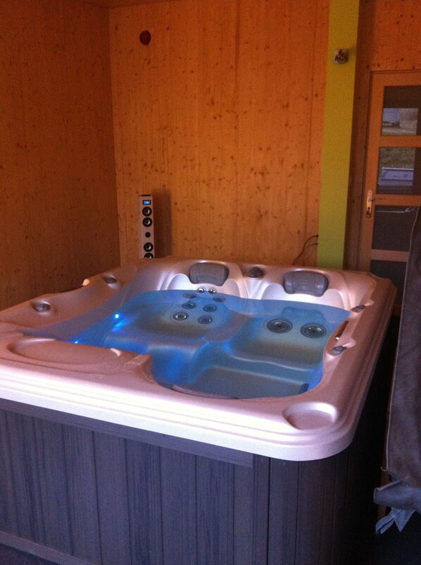 Un bain à remous doté de plusieurs jets, d’un panneau de commande et d’un mur en bois.