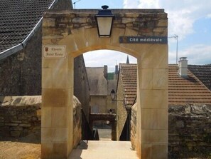 Un arco de entrada con la leyenda 'Cité médiévale' que da paso a un edificio de piedra con tejado de baldosas.
