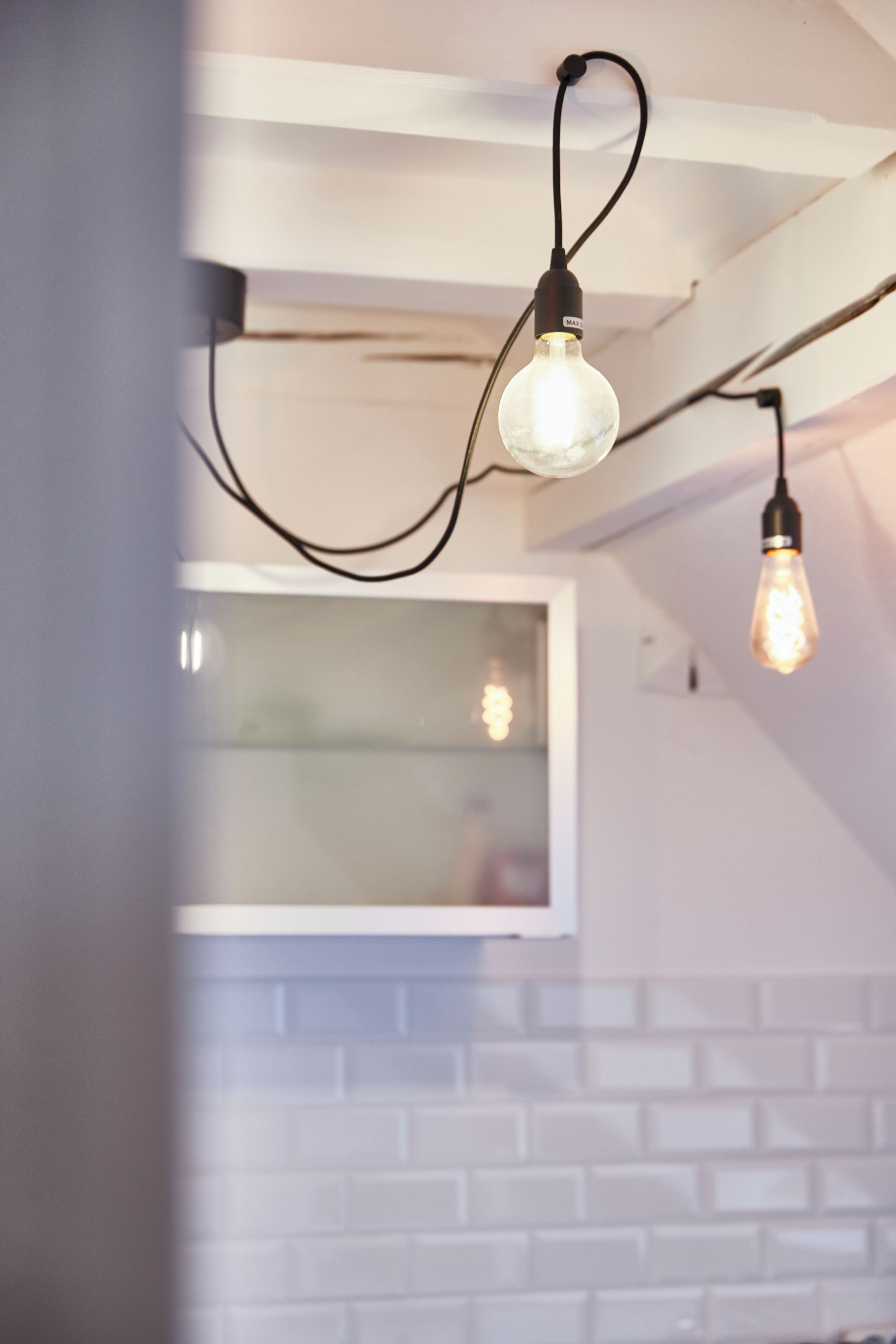 Une cuisine moderne avec un mur de fond en briques blanches et des luminaires suspendus.