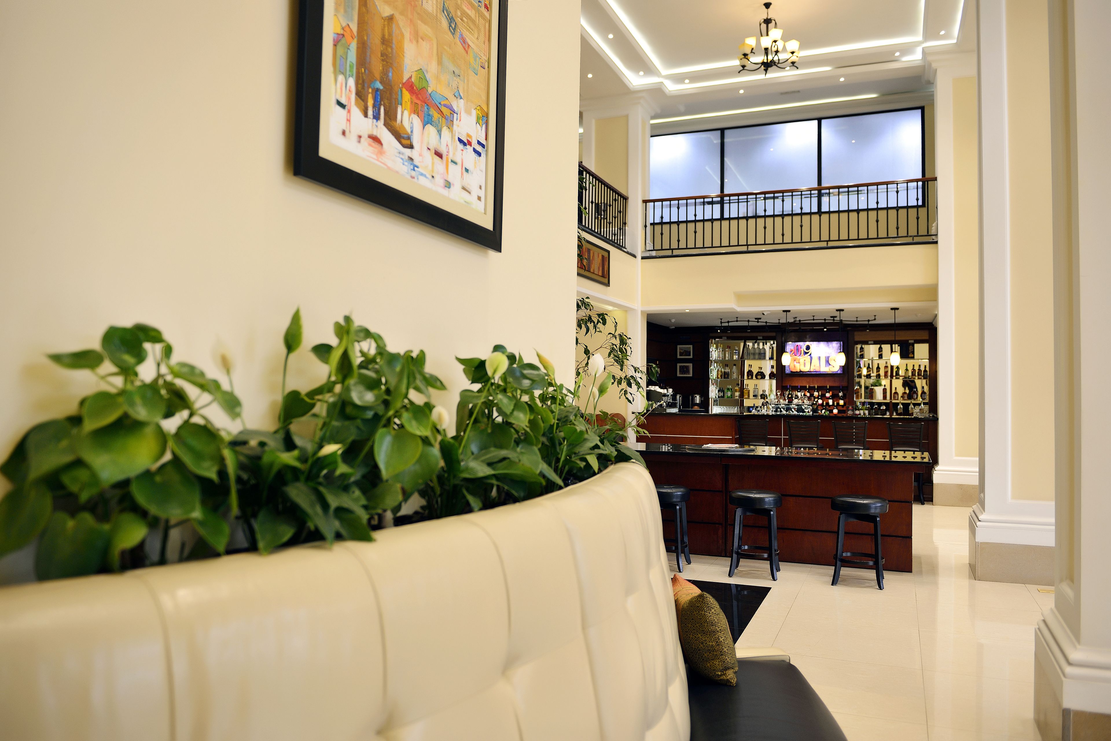 A modern interior with a bar area, a staircase, and a seating area with plants.