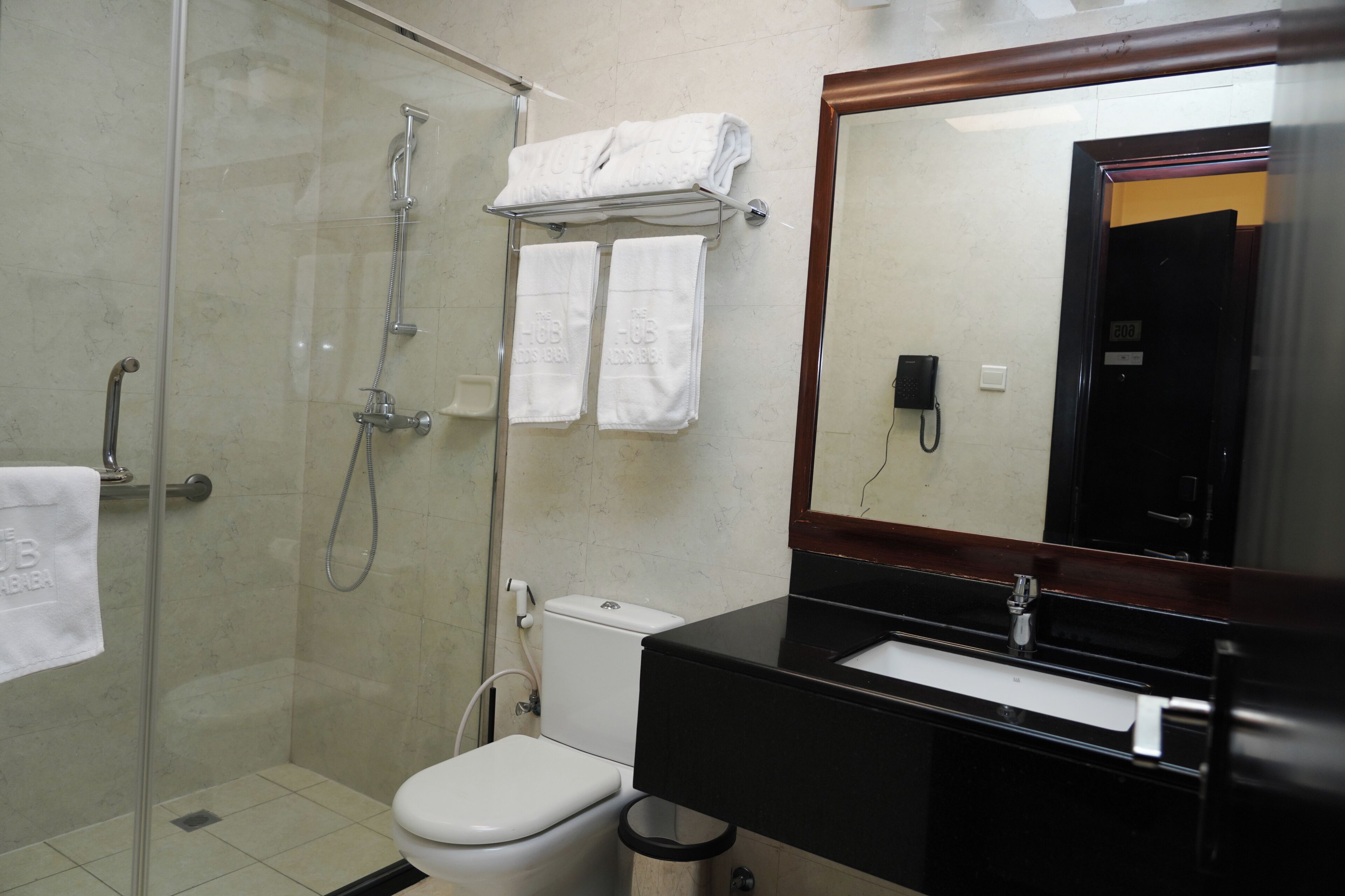 Un baño con ducha separada por vidrio, inodoro, lavamanos y espejo.