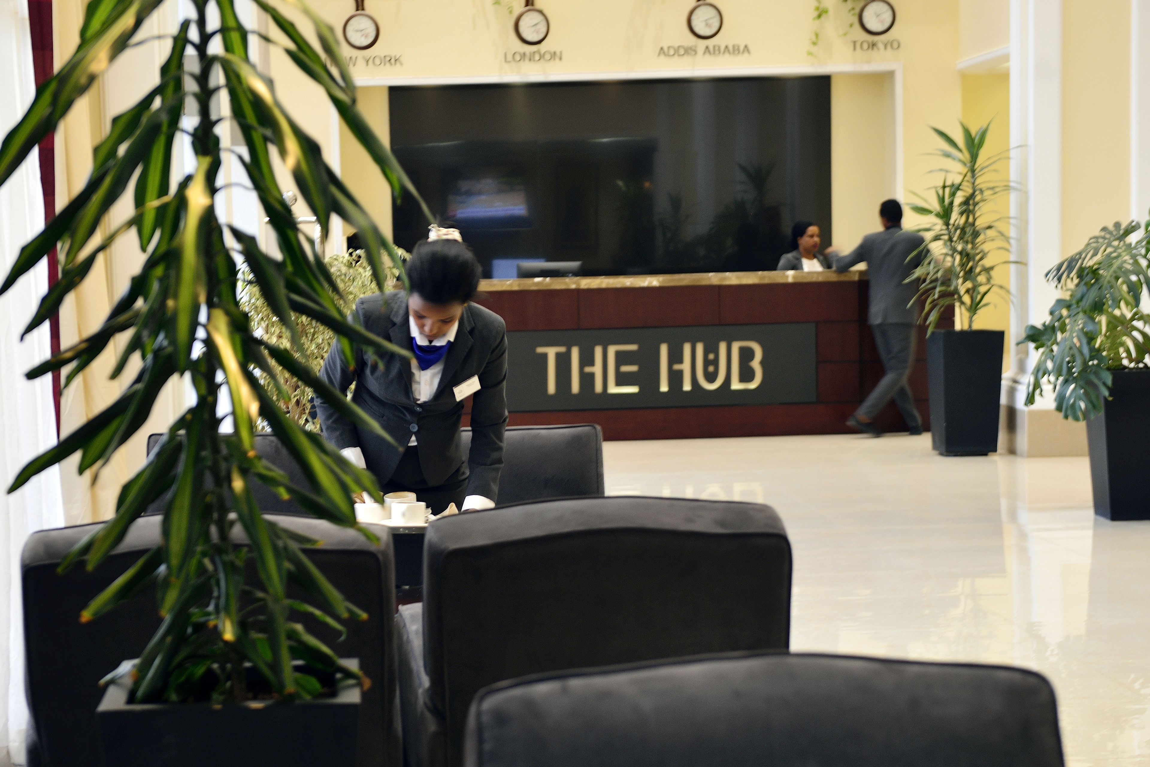 A reception area with a reception desk labeled "THE HUB," a clock, and a sign indicating "LONDON."