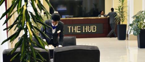 A reception area with a reception desk labeled "THE HUB," a clock, and a sign indicating "LONDON."