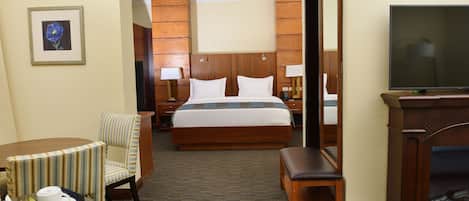 A hotel room with a large bed, a desk with a chair, a television, and a framed picture on the wall.