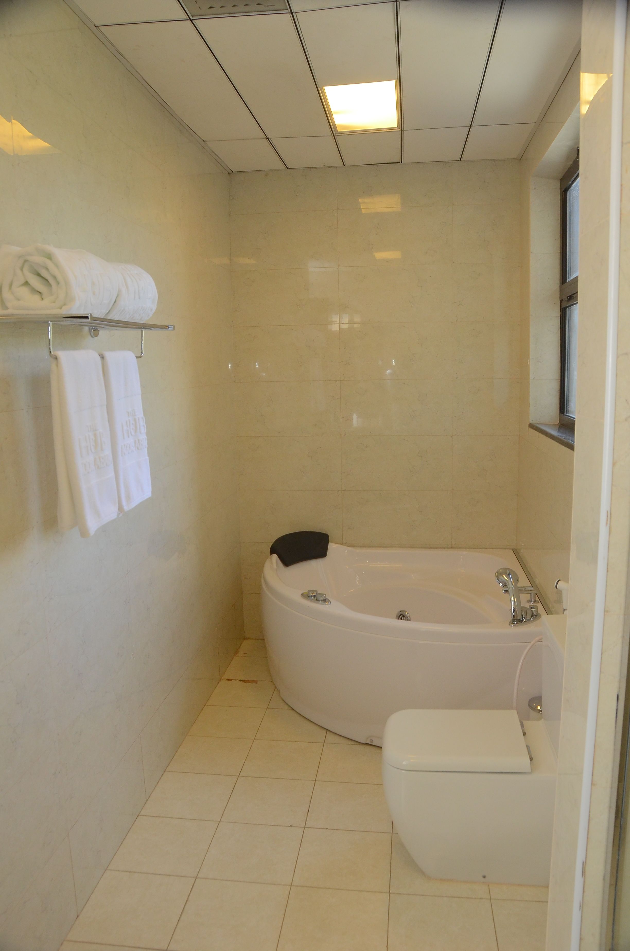 Ein Badezimmer mit einer Badewanne, Toilette und einem Ablagefach mit Handtüchern.