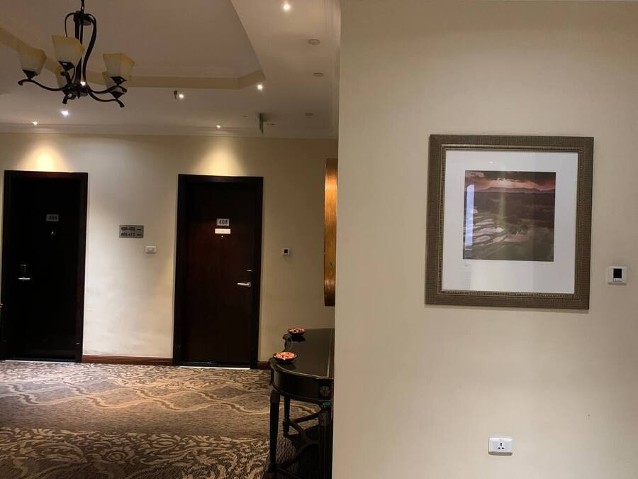 En hotellobby med ett mönstrat golv, en kristallkrona och en inramad tavla på väggen.