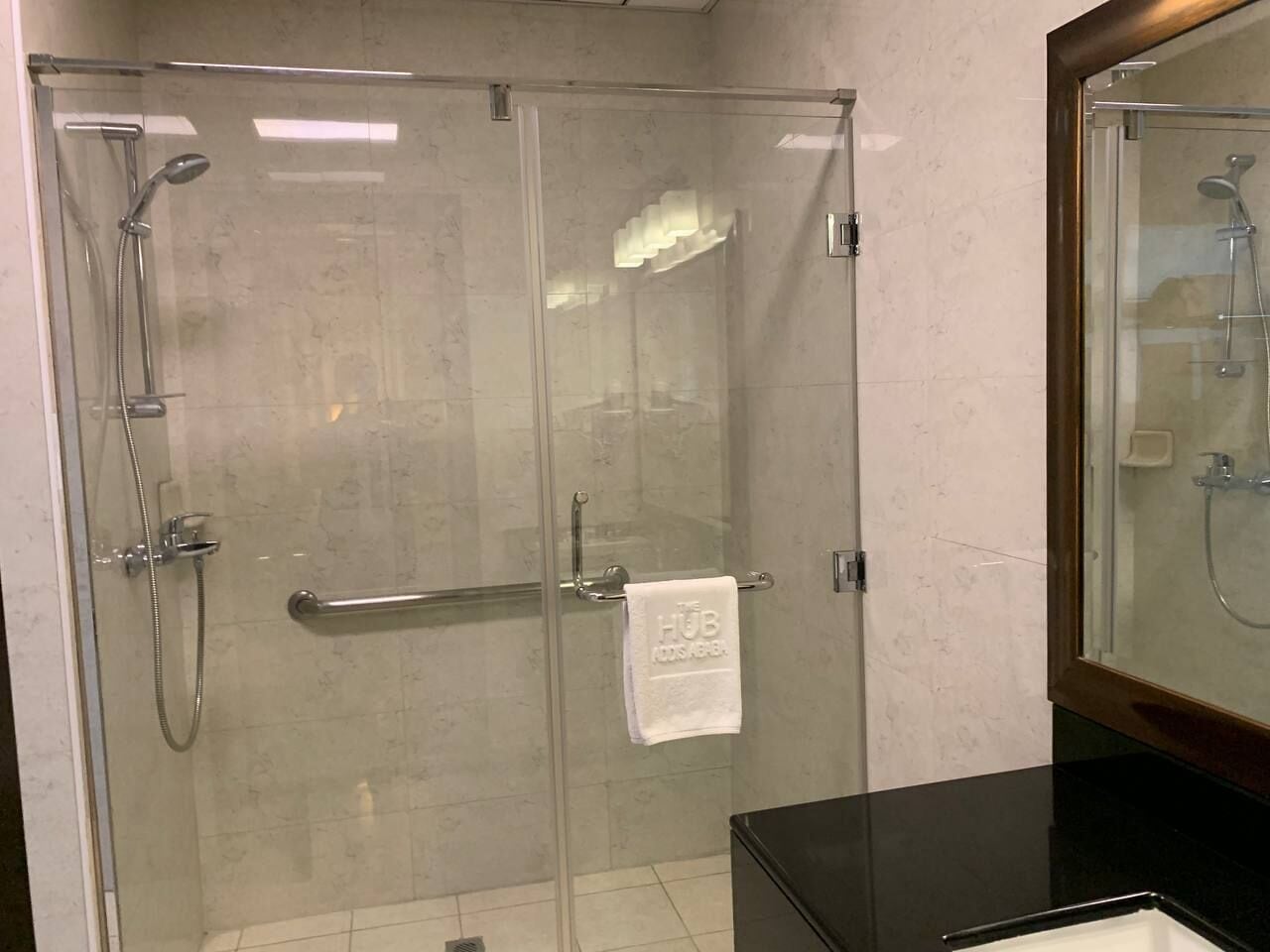 A glass-enclosed shower with a towel rack and a visible towel.