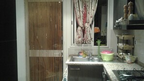 Una cocina con un fregadero, una estufa a gas y un ventanal con cortinas.