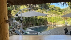 Une terrasse en bois avec une piscine, des chaises longues et des parasols.
