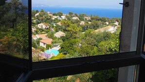 A view from a window overlooking a residential area with houses, greenery, and a clear blue sky. - Beautiful 4 * villa with private heated pool, sea view, 5 minutes from the beach (Fréjus)