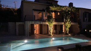 A swimming pool with a patio area, a covered outdoor seating space, and a building with a balcony. - Beautiful 4 * villa with private heated pool, sea view, 5 minutes from the beach (Fréjus)