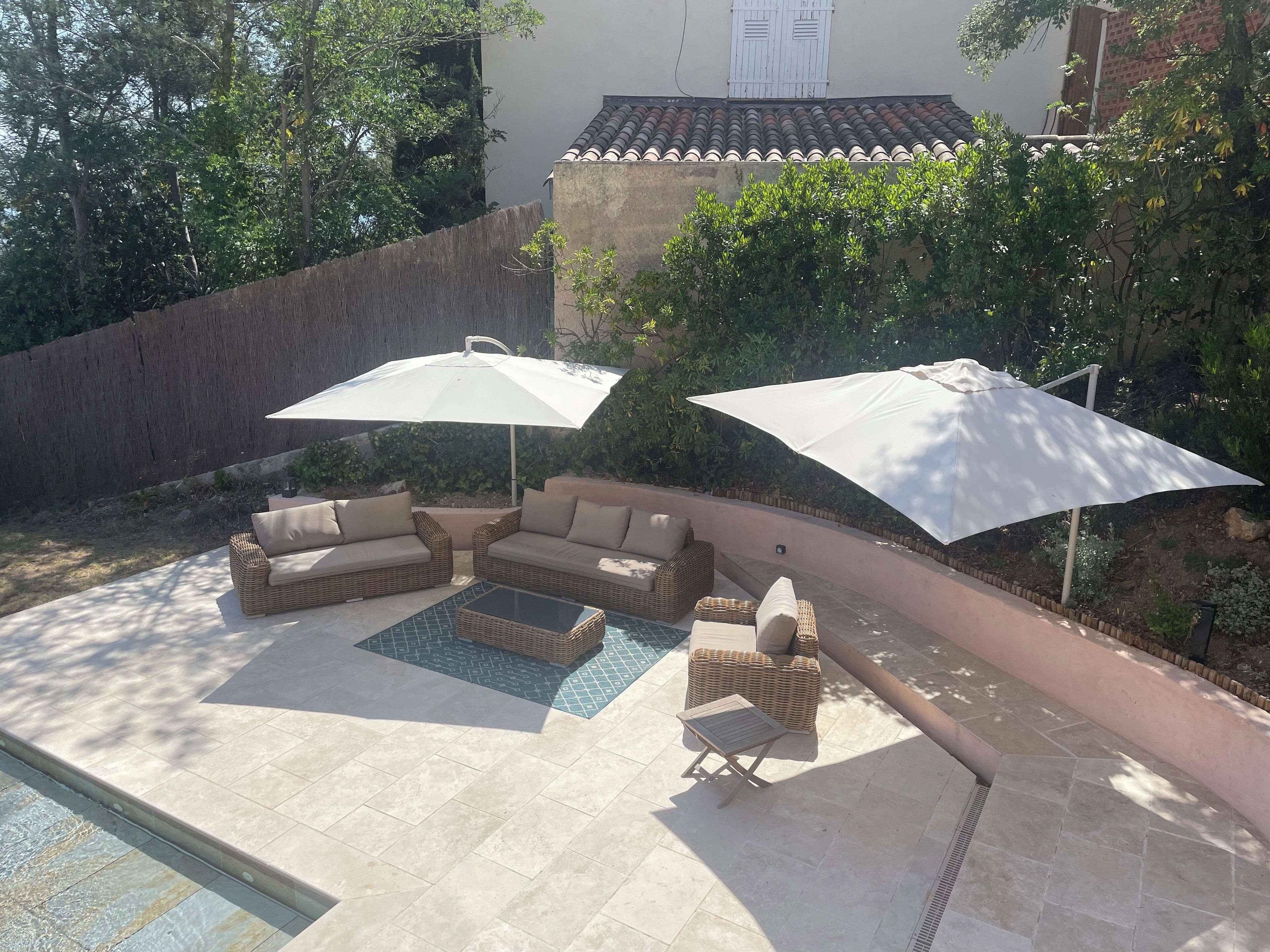 A patio area with a pool, outdoor furniture, and umbrellas.