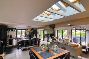 Una cocina moderna con comedor, una sala de estar con sofá y mesa de centro, y un tragaluz grande.