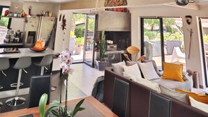 A modern kitchen with a bar area, a dining space with a sofa, and a skylight with hanging decorations.