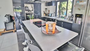 A modern kitchen with a central island, stainless steel appliances, and a large window providing natural light.