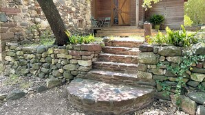A stone staircase leading to a wooden cabin with a porch and outdoor seating.