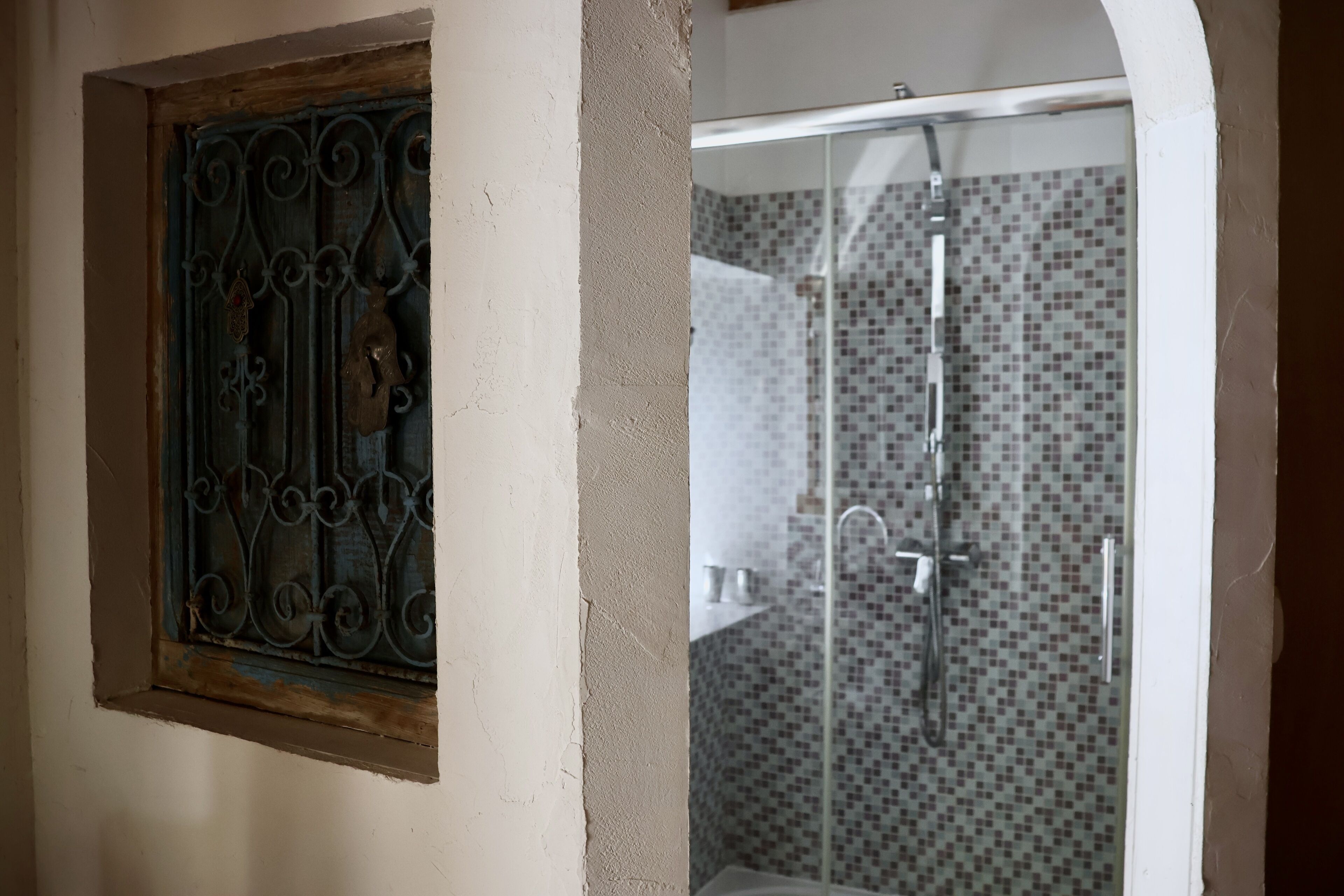 A bathroom with a shower and a window with decorative metal bars.